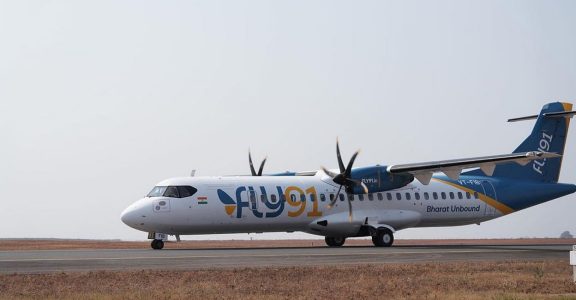 Aerial view of an airplane soaring above vibrant Indian cities, symbolizing FLY91's regional air travel services. | FLY91 Launch | India Connectivity