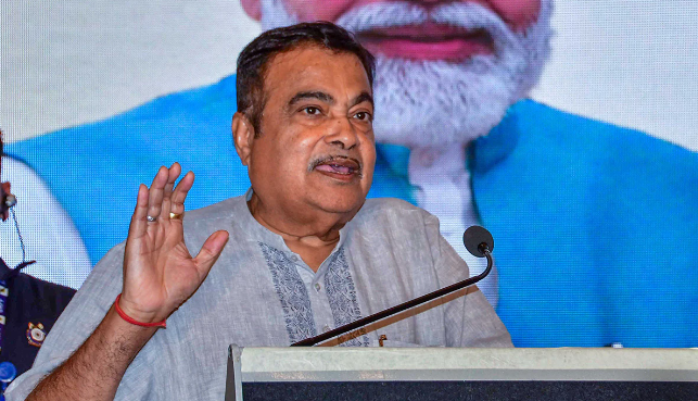 Nitin Gadkari addressing a press conference, surrounded by supporters and banners displaying his manifesto goals