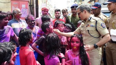 Nagpur Police Commissioner Dr. Ravindra Singal playing Holi with children and distributing sweets.