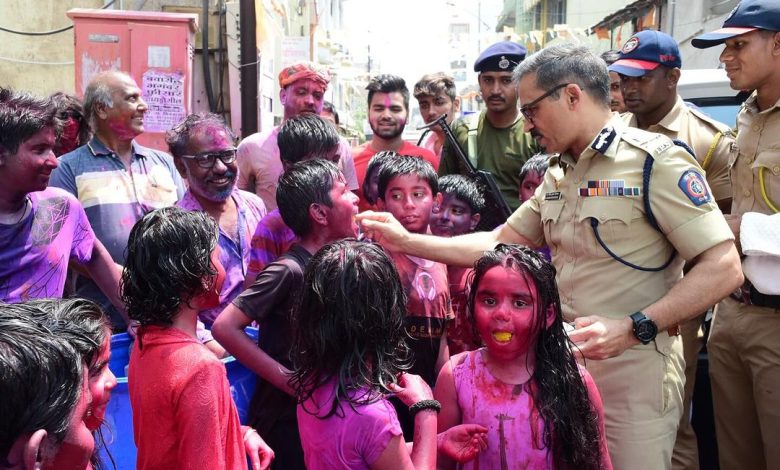 Nagpur Police Commissioner Dr. Ravindra Singal playing Holi with children and distributing sweets.