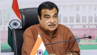 Nitin Gadkari addressing the media about the new toll system, with highways in the background.