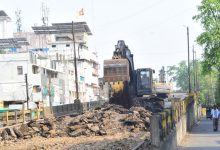 A halted flyover demolition site with cranes and debris under a cloudy Nagpur sky.