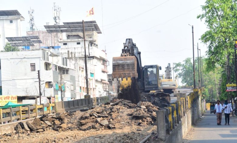 A halted flyover demolition site with cranes and debris under a cloudy Nagpur sky.